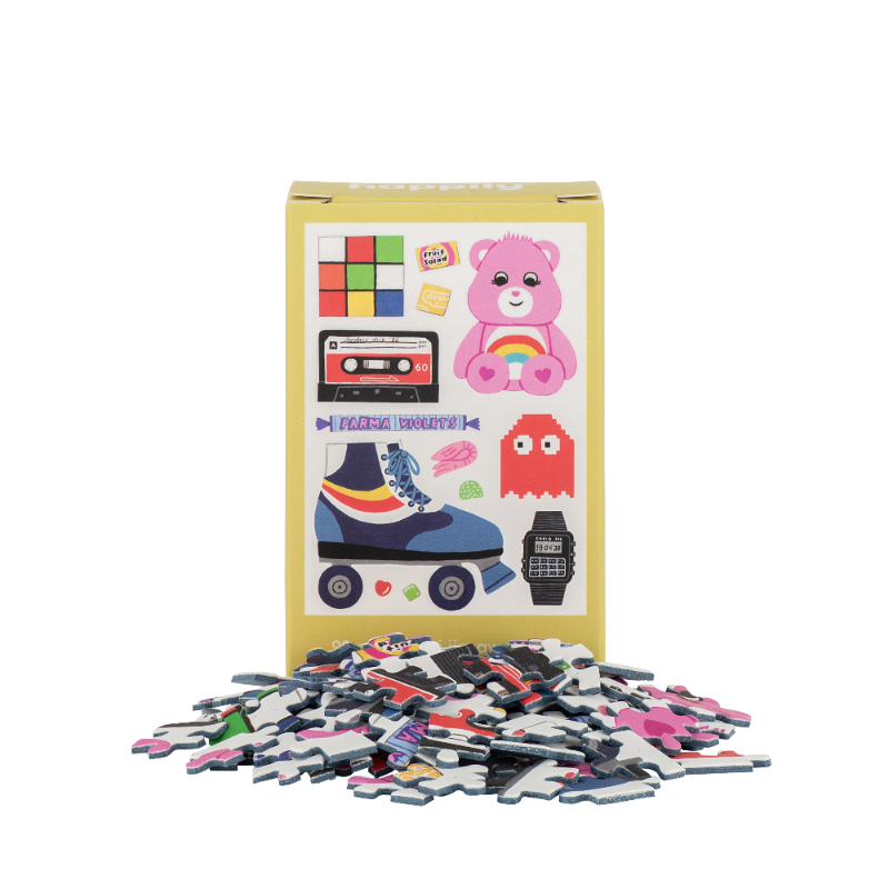 Pile of colorful puzzle pieces in front of a box with illustrations on a white background