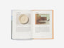 Open book with images of a ceramic plate and a room interior on a white background