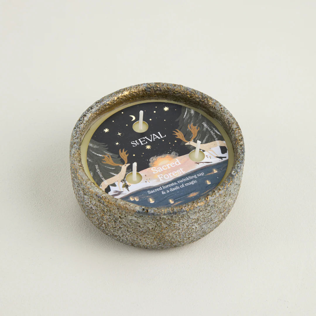 Ceramic candle holder with decorative label on a light background