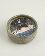 Ceramic candle holder with decorative label on a light background