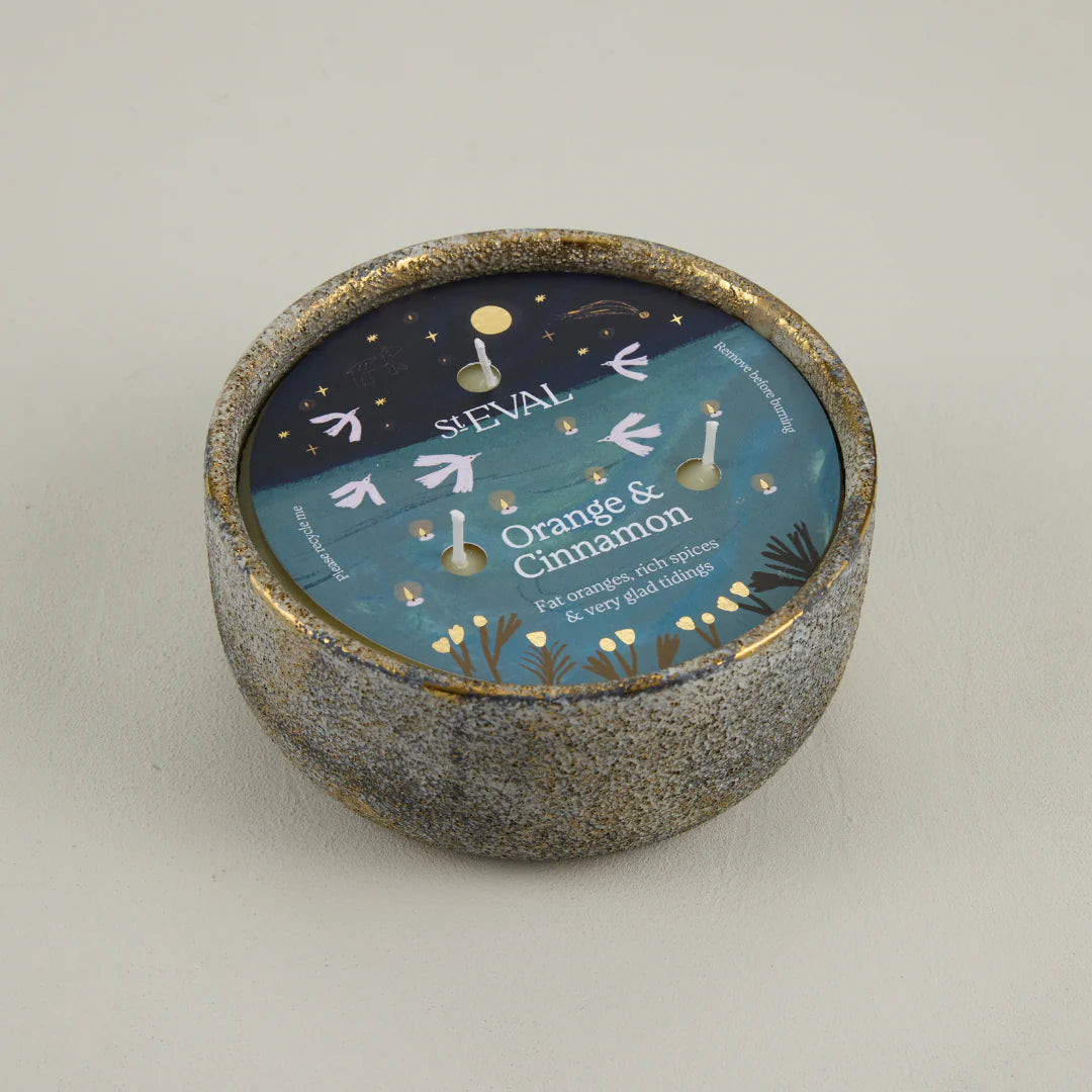 Ceramic candle holder with a blue label on a light gray background