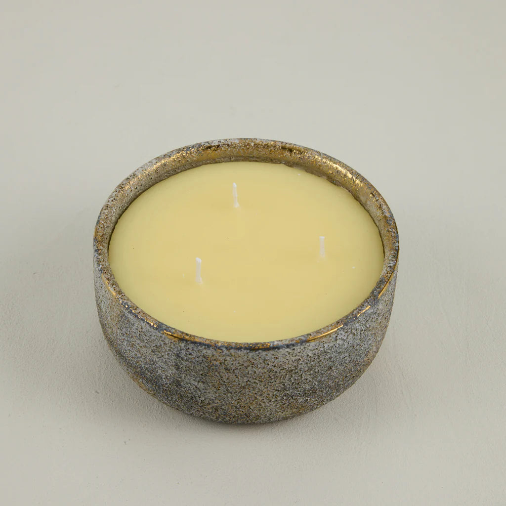 Candle in a textured ceramic holder on a neutral background