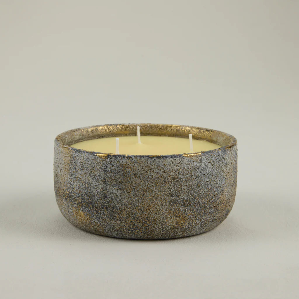 Ceramic bowl with a candle inside on a plain background