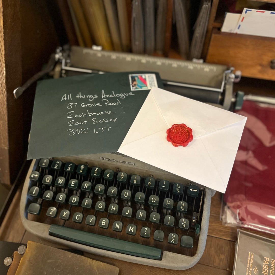 Vintage typewriter with a letter and envelope on top, set against a wooden background.