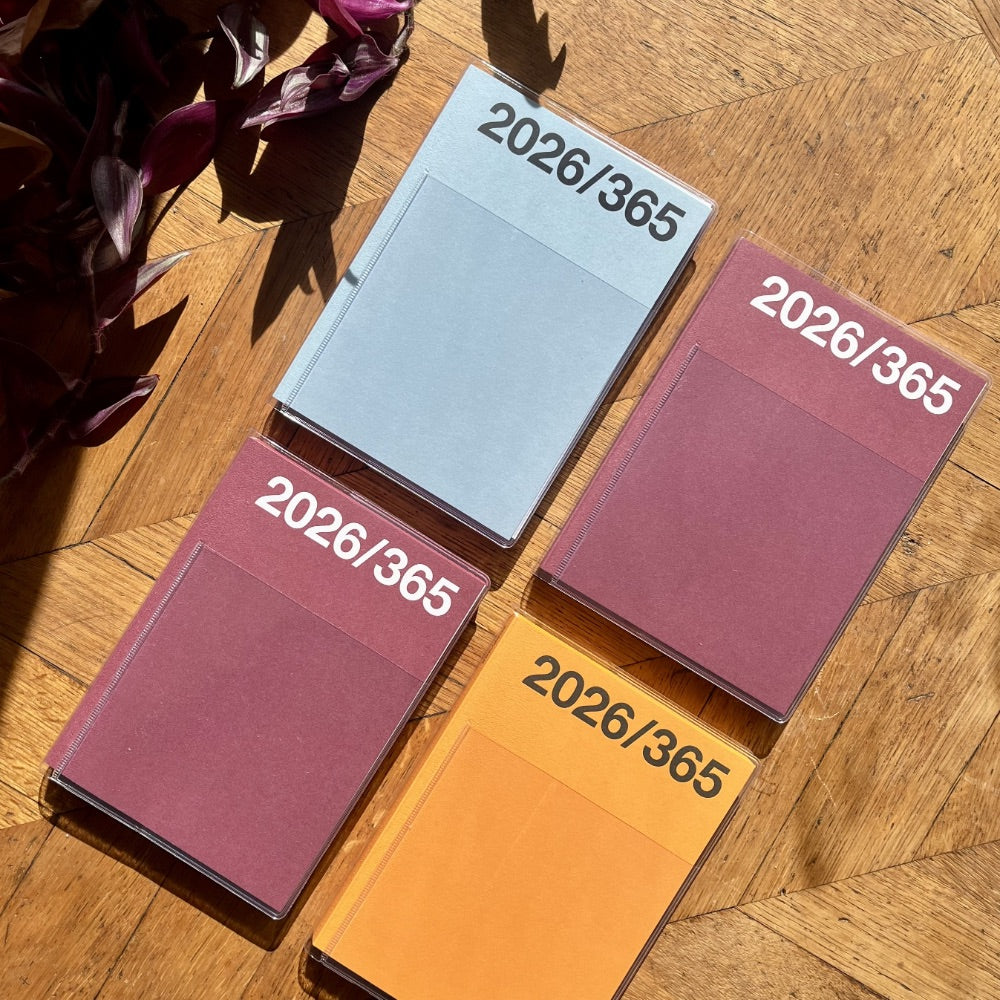Four colorful planners labeled '2026/365' on a wooden surface.