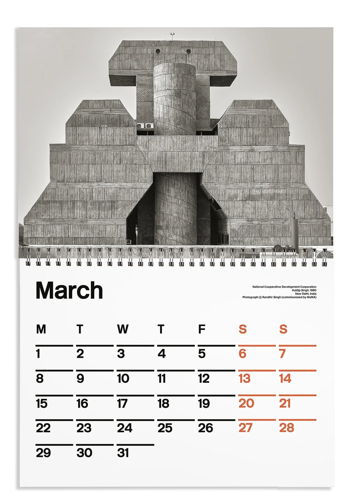 A spiral-bound calendar page featuring a large black-and-white architectural photograph of a concrete building on the top half, with a March calendar grid on the bottom half. The days of the week are printed in black, with Sundays highlighted in red-orange.