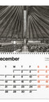 A spiral-bound December calendar page featuring a black-and-white architectural photograph of a large domed interior above a monthly calendar grid with black and orange dates on a white page.