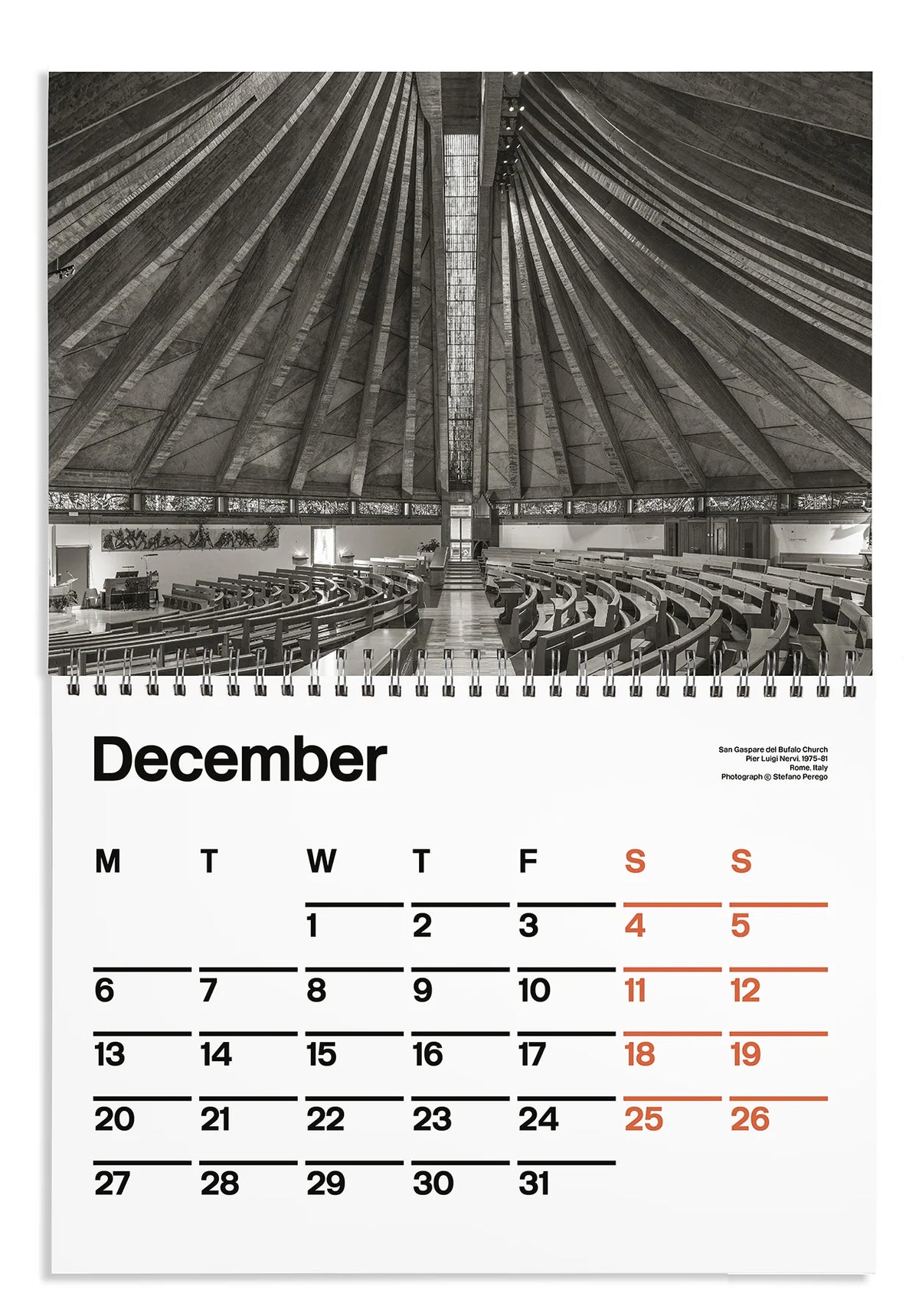 A spiral-bound December calendar page featuring a black-and-white architectural photograph of a large domed interior above a monthly calendar grid with black and orange dates on a white page.