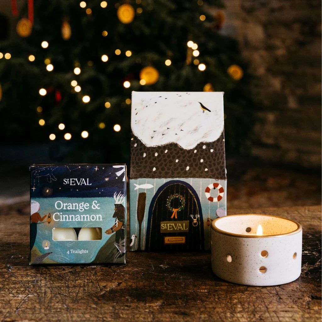 Decorative candles and packaging with a Christmas tree in the background
