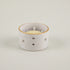Speckled ceramic candle holder with a white candle on a light gray background