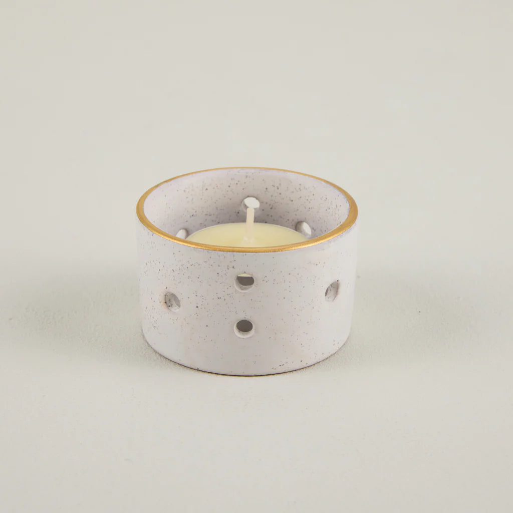 Speckled ceramic candle holder with a white candle on a light gray background