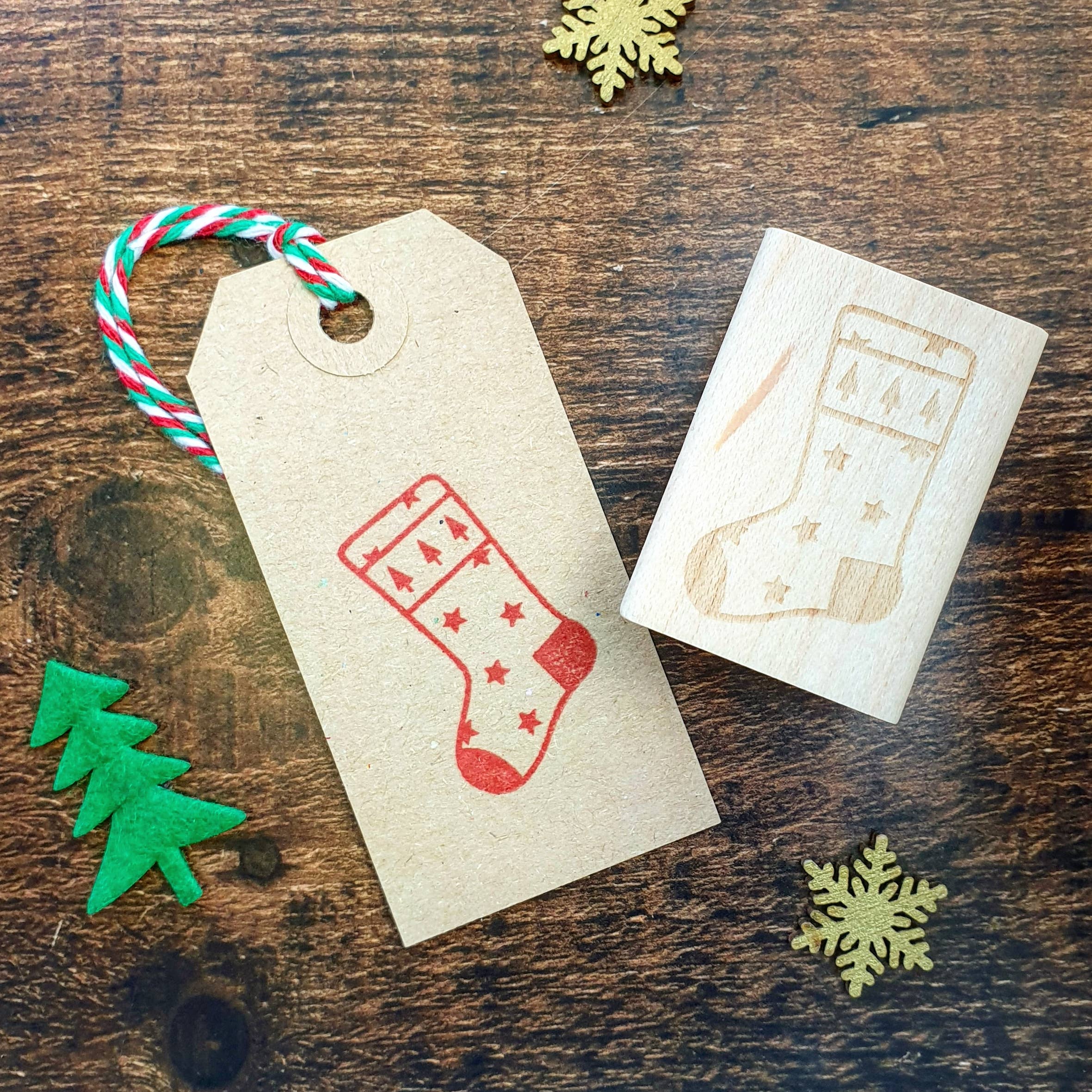 Christmas-themed stamp on a paper tag with decorative elements on a wooden surface