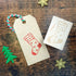 Christmas-themed stamp on a paper tag with decorative elements on a wooden surface