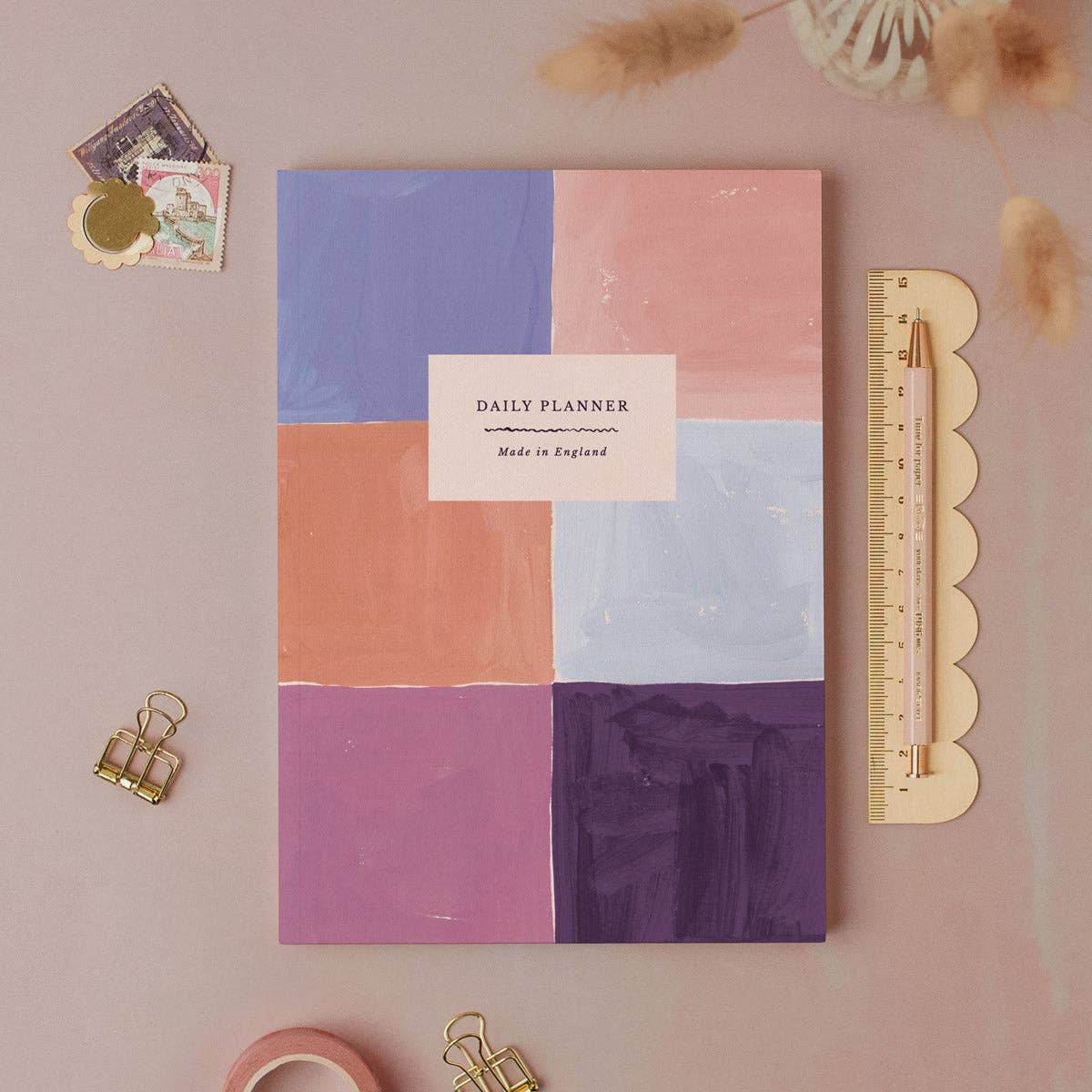 Colorful daily planner with stationery items on a pink background