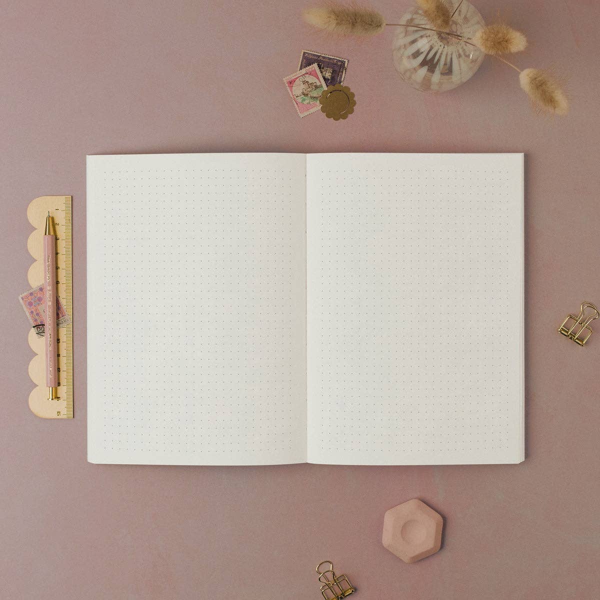 Open notebook on a pink surface with decorative items around