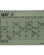A 2027 spiral-bound notebook calendar with a light sage green cover and black printed grid layout, shown on a plain white background.