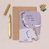 Greeting card with elephant design and 'hello little one' text, next to a pen and envelope on a beige background.