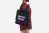 Person wearing a black tote bag with 'EMOTIONAL BAGGAGE' text on a white background