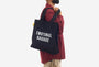Person wearing a black tote bag with 'EMOTIONAL BAGGAGE' text on a white background