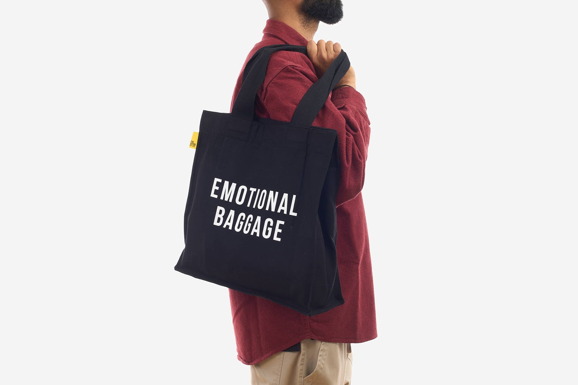 Person wearing a black tote bag with 'EMOTIONAL BAGGAGE' text on a white background