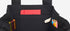 Black tote bag with colorful pens and a red pocket on a white background