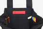 Black tote bag with colorful pens and a red pocket on a white background