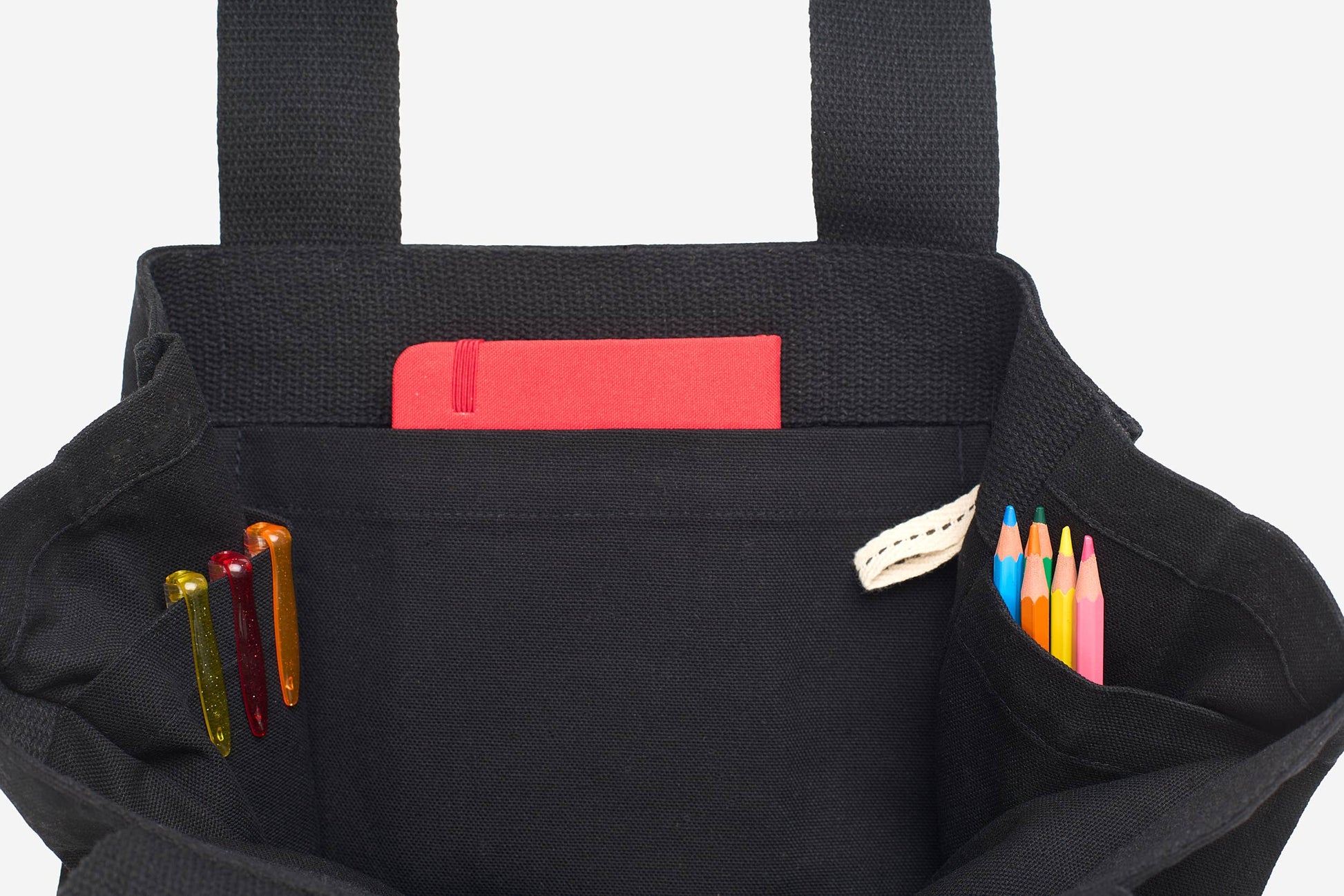 Black tote bag with colorful pens and a red pocket on a white background