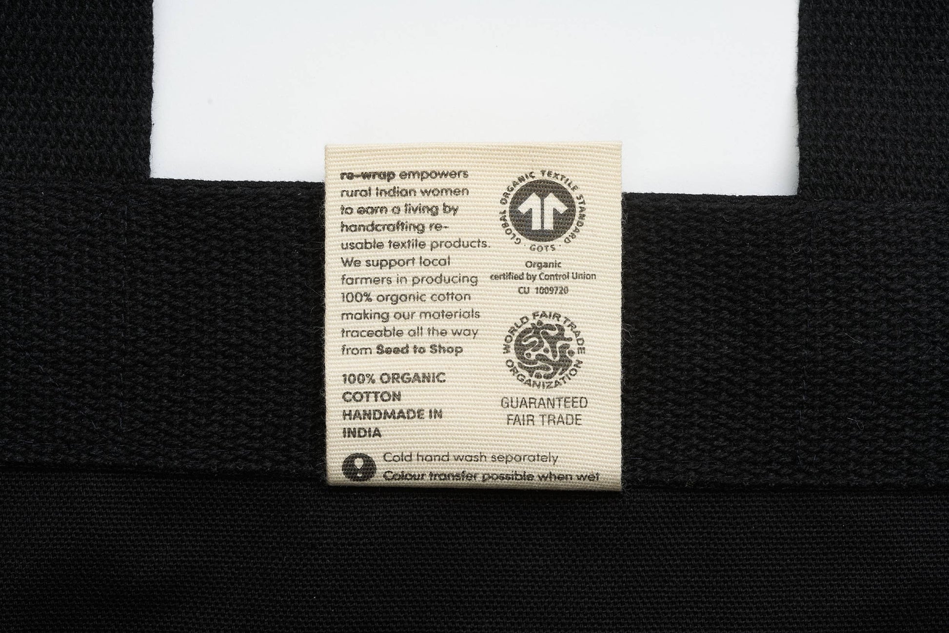 Label on a black garment with text about organic cotton and fair trade practices.
