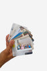 Hand holding a stack of photo cards with images on a white background
