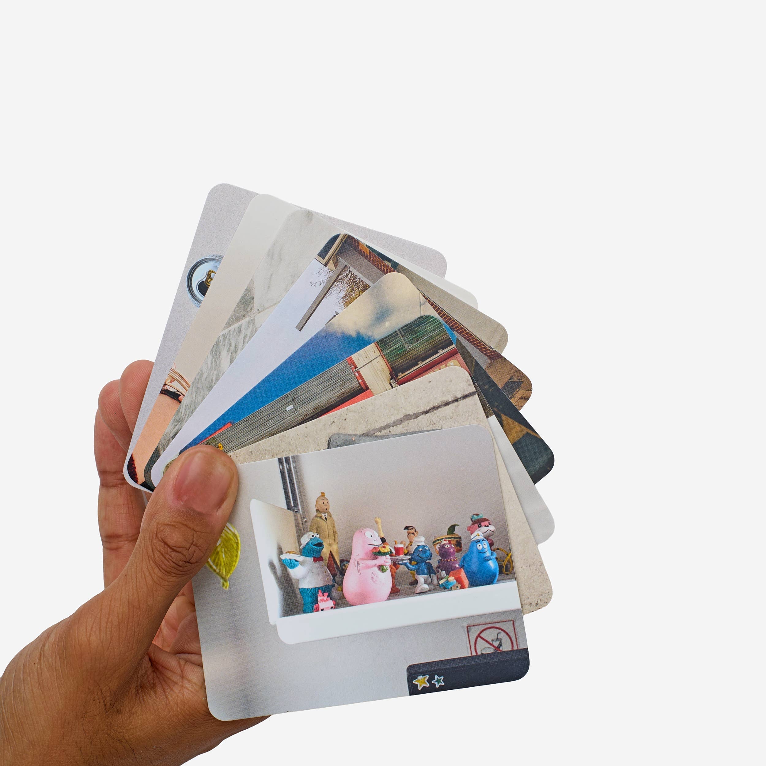 Hand holding a stack of photo cards with images on a white background