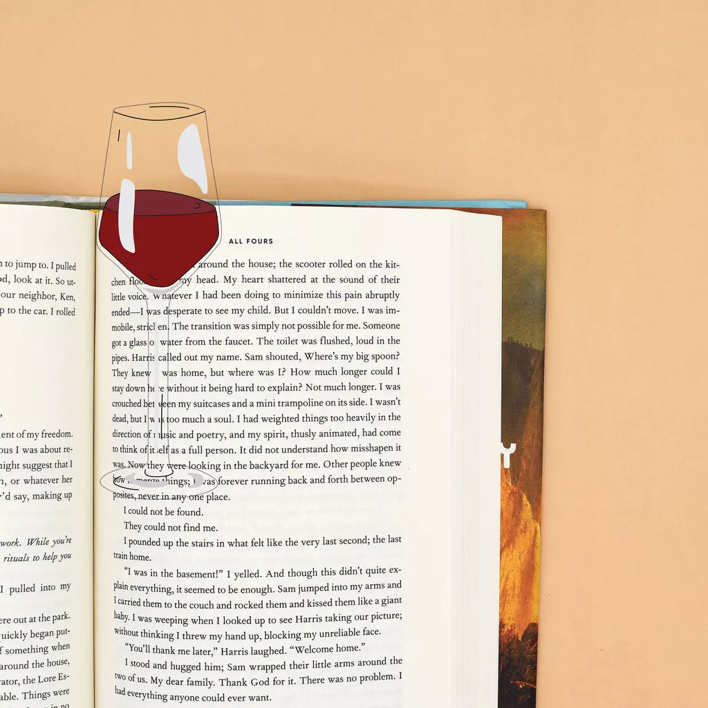 Open book with a wine glass bookmark on a beige background