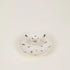 White ceramic plate with gold speckles on a light beige background