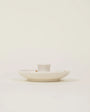 White ceramic dish with a small cup on a light beige background