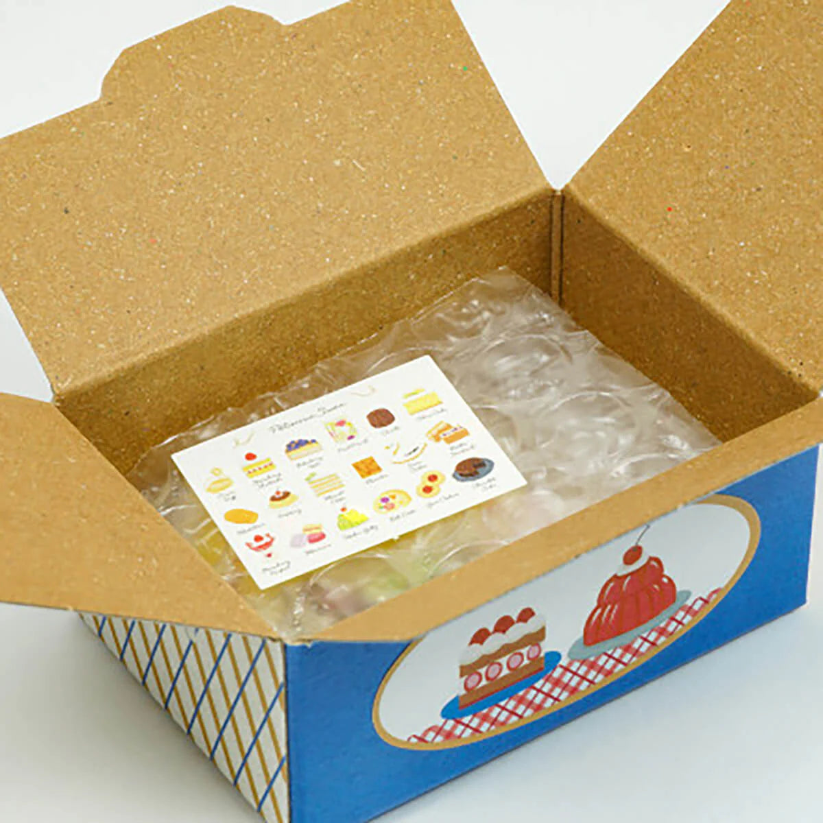 Open cardboard box with a plastic-wrapped item and a card inside, on a white background