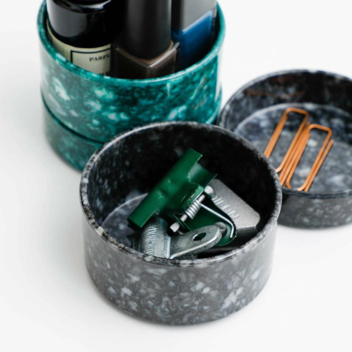 Set of nail polish bottles in a green container with open compartments on a white background