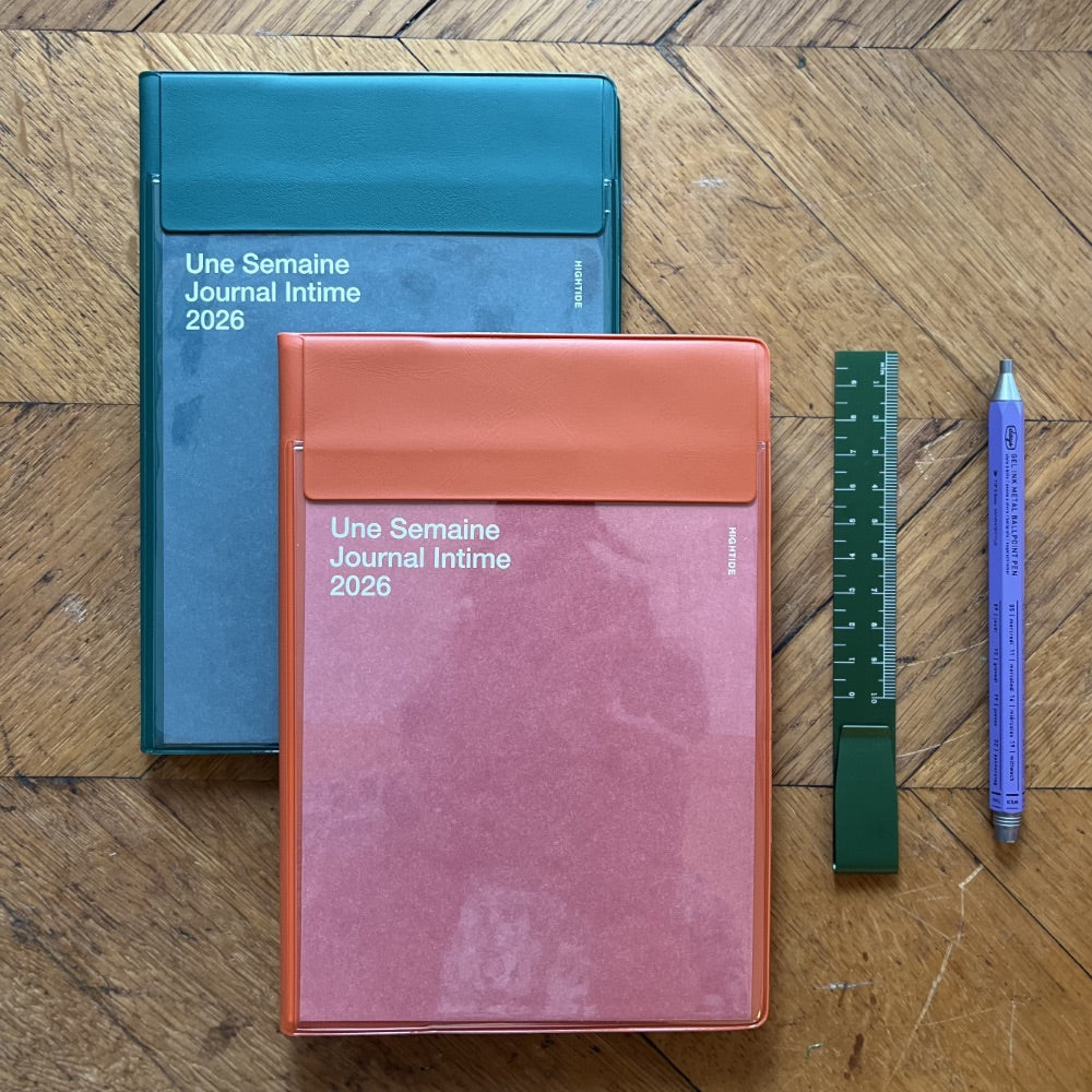 Two notebooks with different colored covers on a wooden surface, accompanied by a ruler and pen.