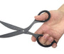Hand holding a pair of black scissors against a white background