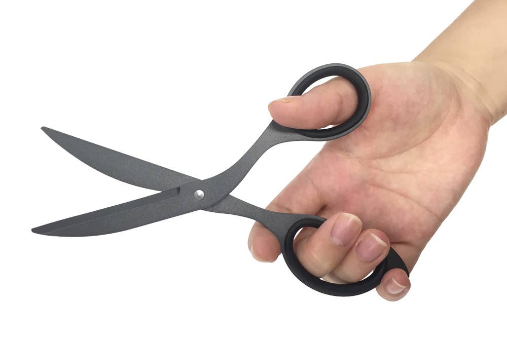 Hand holding a pair of black scissors against a white background