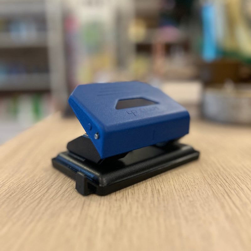 Blue and black hole puncher on a wooden surface with a blurred background