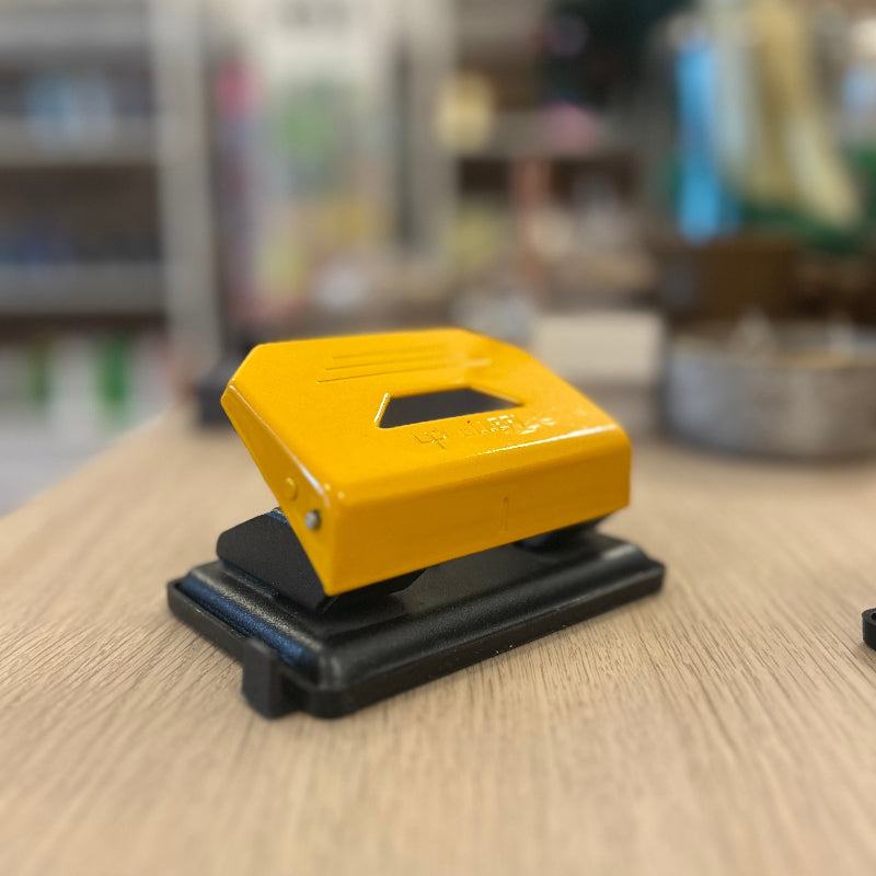Yellow hole puncher on a wooden surface with a blurred background