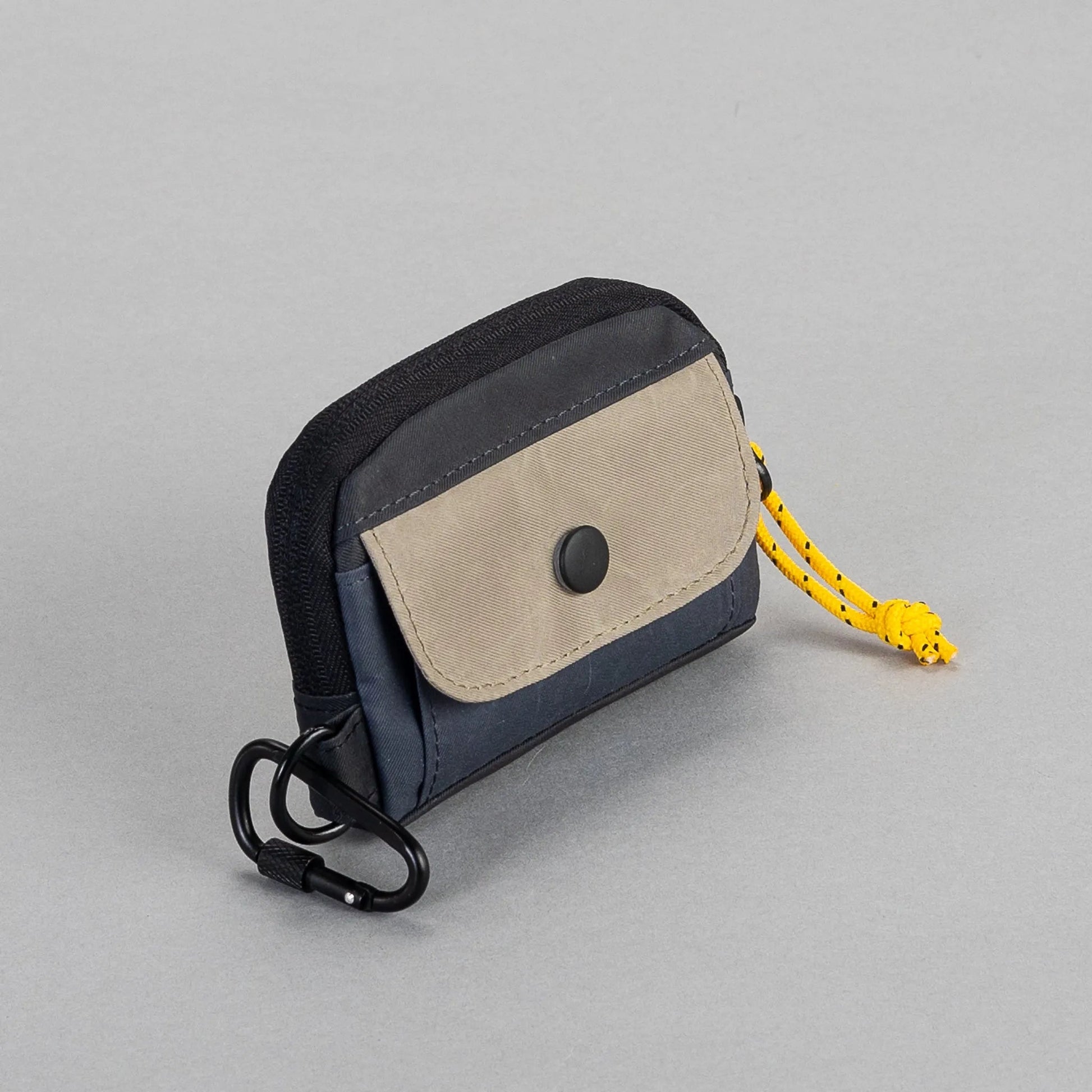 Small keychain pouch with a black strap and yellow lanyard on a gray background