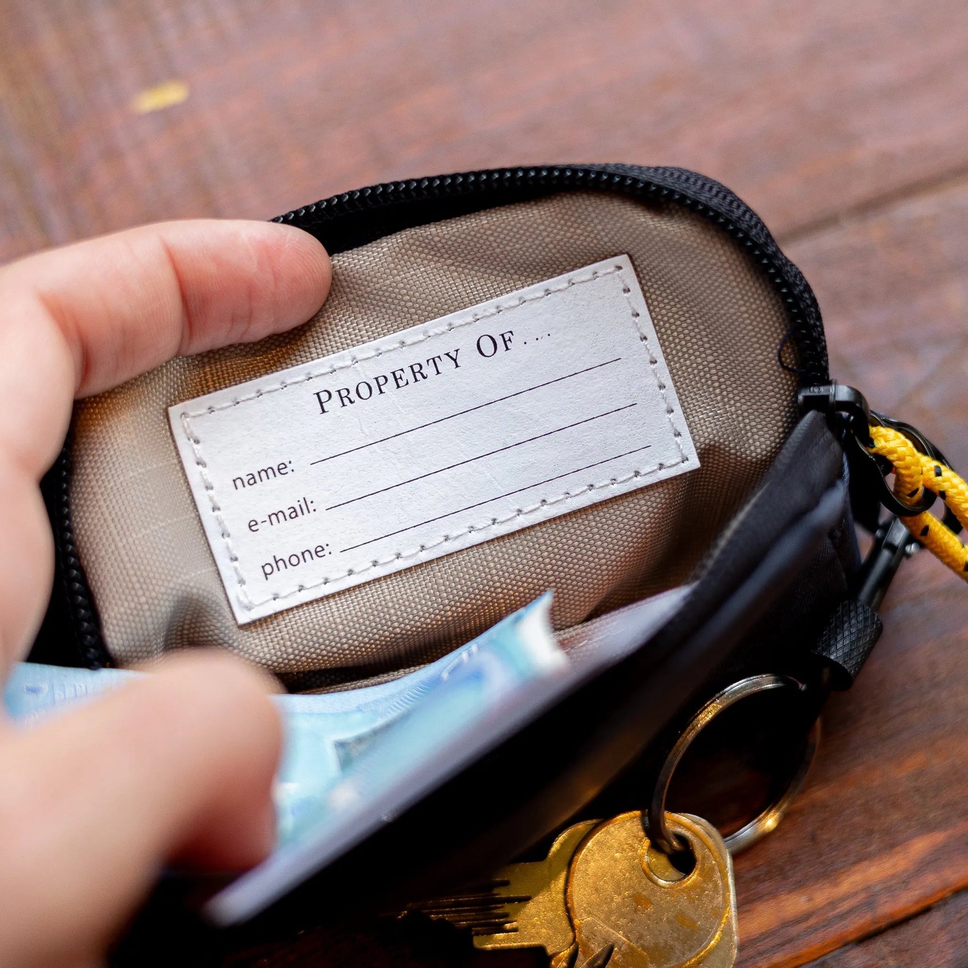Keychain with a labeled pouch and keys on a wooden surface
