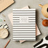 Striped notebook on a textured surface with stationery items