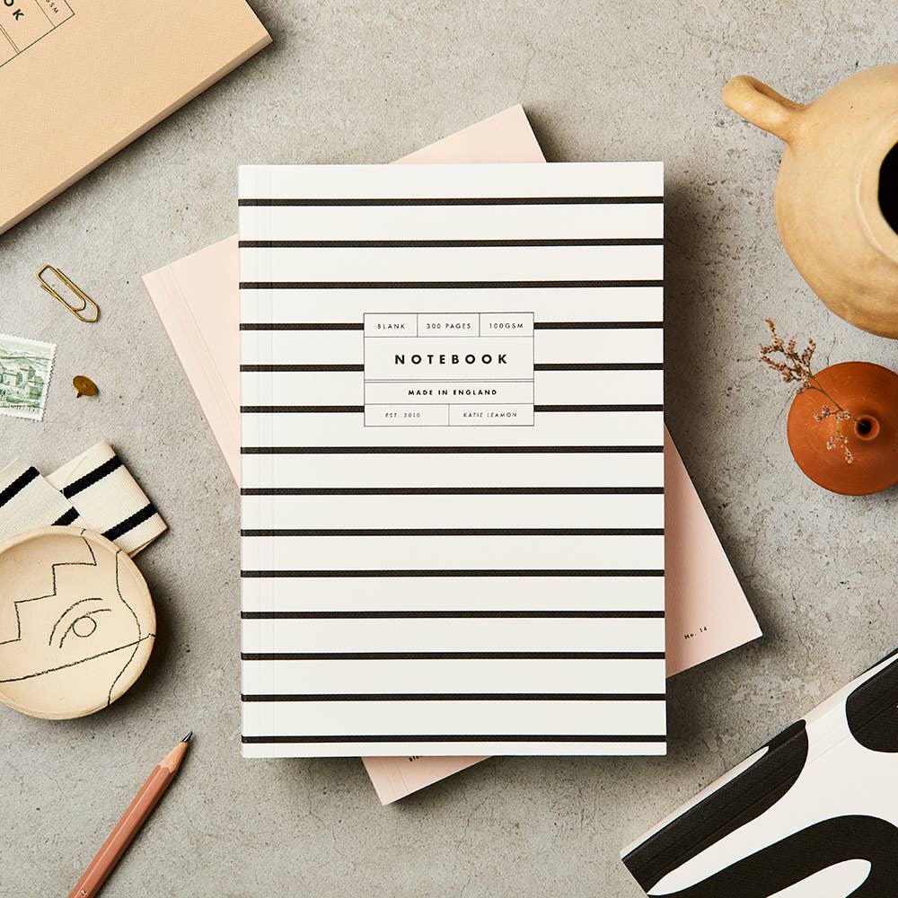 Striped notebook on a textured surface with stationery items