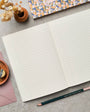 Open notebook with lined pages on a gray surface, surrounded by stationery items.