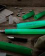 Green fountain pens and components on a wooden surface