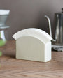 White ceramic Kinto Paper Filter Stand on a wooden surface with kitchen items in the background