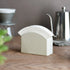 White ceramic Kinto Paper Filter Stand on a wooden surface with kitchen items in the background