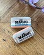 Two Magic Koh-I-Noor erasers on a wooden surface with purple flowers in the background.