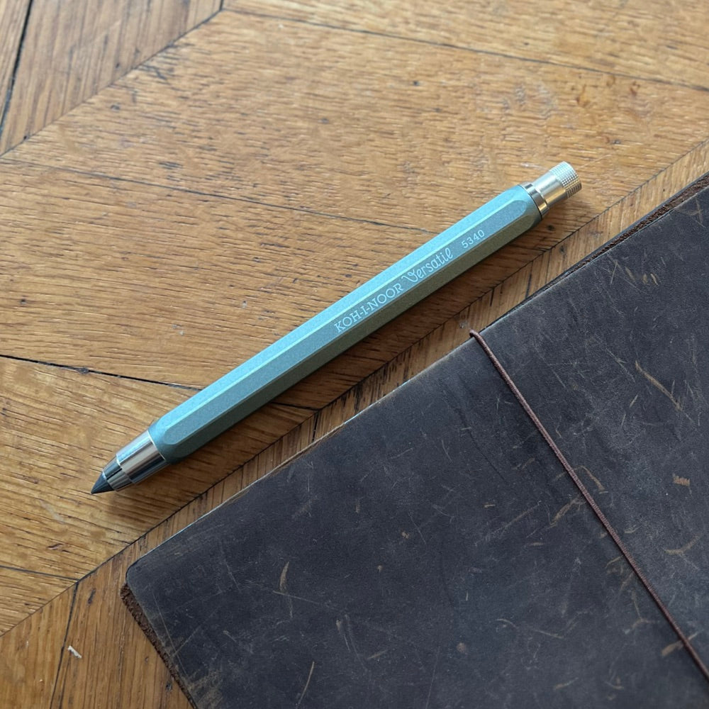 Mechanical pencil on a wooden surface with a leather notebook